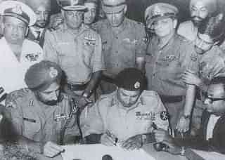Lt Gen Niazi signing the instrument of surrender (1971) under the gaze of Lt Gen Aurora as other army officials look on.