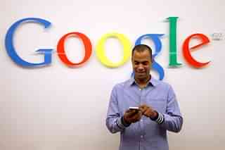 A man using a smartphone in front of the Google logo (Representative image) (Adam Berry/Getty Images)