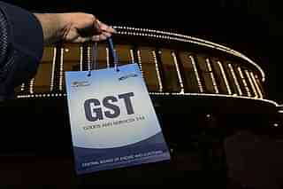 A man holds a sign reading ‘GST’ outside the Parliament building. (photo by Arun Sharma/Hindustan Times via Getty Images)