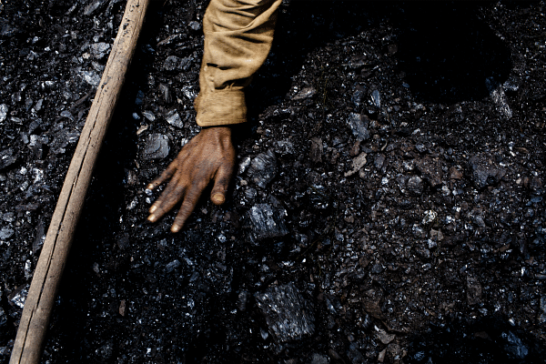 A coal worker levels out the coal in a crate. (Daniel Berehulak/Getty Images)