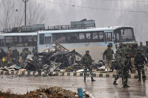 Security forces near the damaged vehicles at Lethpora on the Jammu-Srinagar highway. (Waseem Andrabi/Hindustan Times via Getty Images)