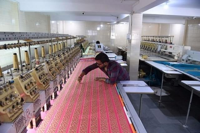 An Indian textile maker works on an embroidery machine at a workshop. (SAM PANTHAKY/AFP/GettyImages)