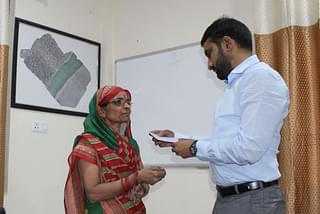 Singh hands over the cheque of compensation to a resident who has registered her house.