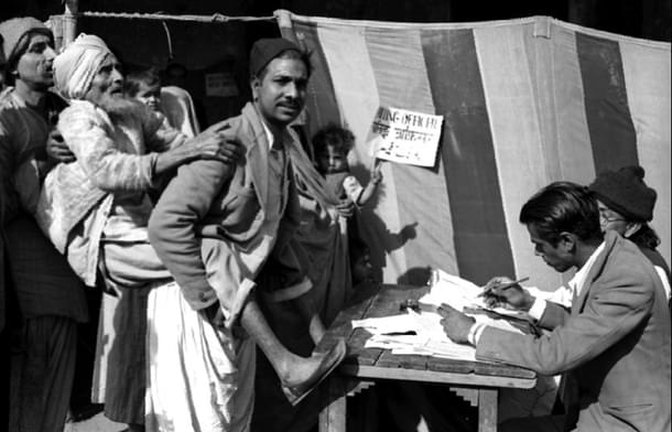 A blind old man is being brought to a polling booth by his son, to help him to cast his vote during the first general elections in 1952, near a polling station in Jama Masjid area in Delhi. 