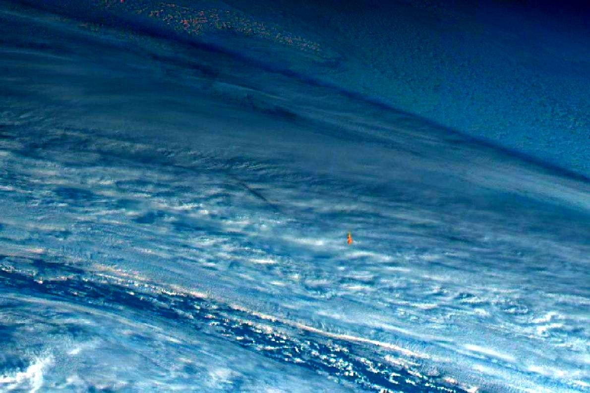 The small bright orange fireball against the blue-white background of earth (@simon_sat/Twitter)&nbsp;