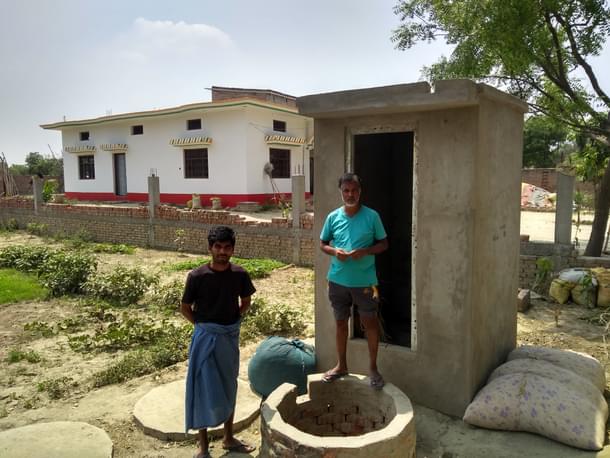 Rajender and Jaisingh Yadav standing in front of  an under-construction toilet in Tamauli. (Prakhar Gupta/Swarajya)