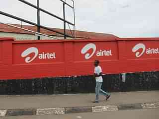 A man moves past a row of Airtel logos painted on a wall. (Flickr/nchenga)
