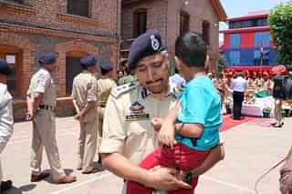A J&amp;K policeman with Arshad’s four-year-old son in the wreath-laying ceremony (Source: @JmuKmrPolice/Twitter)