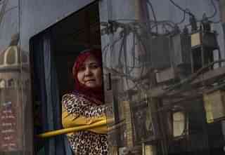A Uyghur woman looks out the window as she rides in a bus. (Kevin Frayer/Getty Images)
