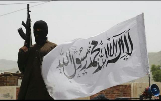 A Taliban fighter with the group’s flag. (via Twitter)