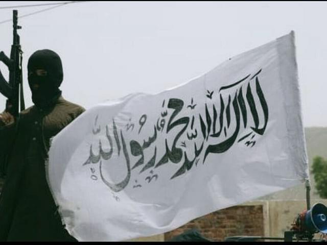 A Taliban fighter with the group’s flag. (via Twitter)