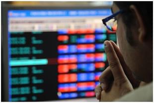 An investor looking at a screen displaying stocks. 