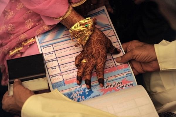 An Indian Muslim bride puts a thumb impression on a marriage certificate in the presence of religious leaders and a relative (representative image) (SAM PANTHAKY/AFP/GettyImages)