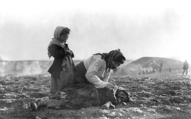 An Armenian woman kneeling beside a dead child in a field “within sight of help and safety at Aleppo. (Wikimedia Commons)