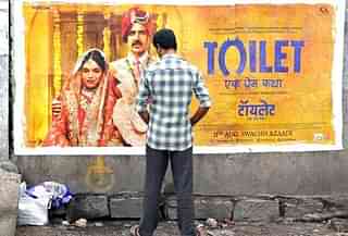 An Indian man urinates on a wall on the roadside in front of a poster for the Hindi film ‘Toilet: Ek Prem Katha’, which is inspired by the true-life tale of one man’s battle to build toilets in his village in rural India. / AFP PHOTO / NOAH SEELAM (Photo: NOAH SEELAM/AFP/Getty Images)&nbsp;