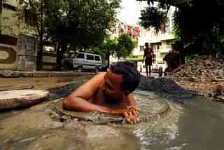 A person engaging in manual scavenging work without protective gear. (Dalit Network/Wikimedia Commons)