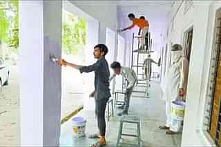 Migrant workers painting walls of schools