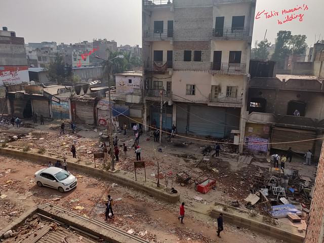 The tallest building in the view is Tahir Hussain’s. On its right (marked in red) is the drain.