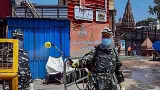 A security personnel with disinfectant outside Kashi Vishwanath temple. (Twitter/<i>Hindustan Times</i>)