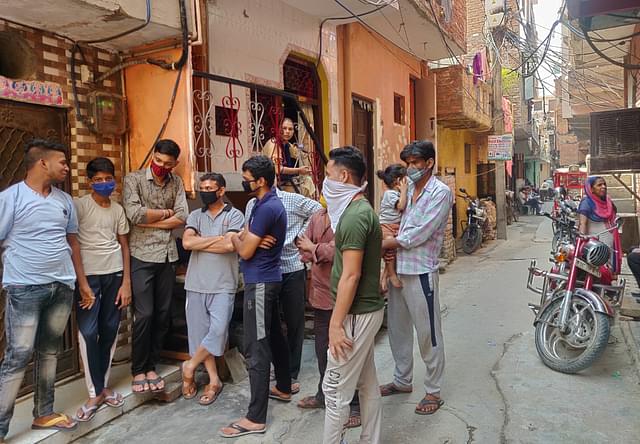 Group of men huddled outside Rahul’s house