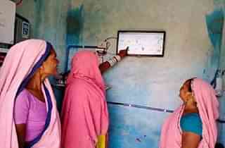 Women monitoring a visual dashboard in the village (PIB)