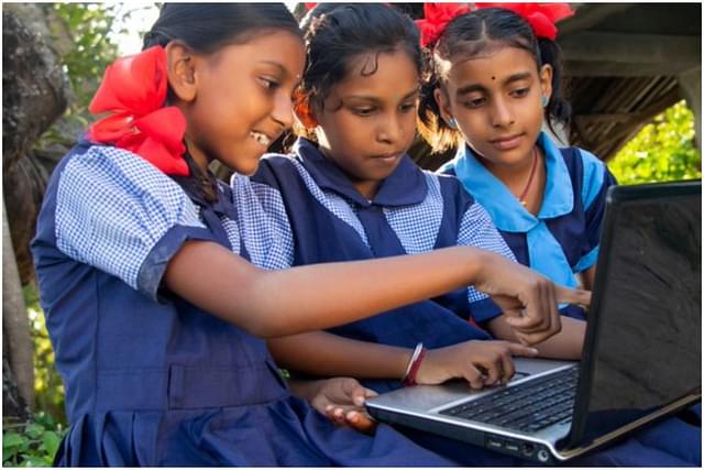 Three schooolchildren learning through a shared computer as not everyone has access to digital devices. 