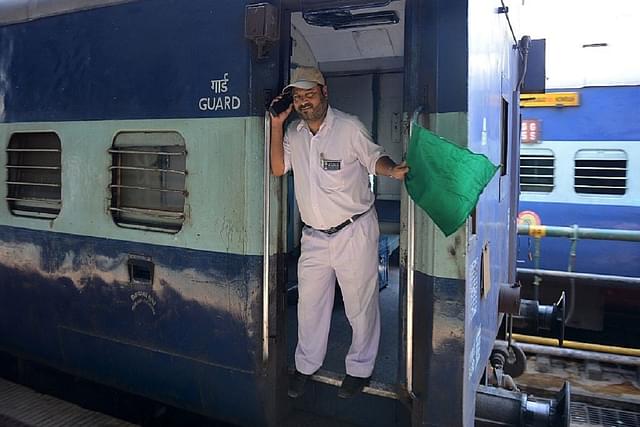 A railway guard signals as a train departs from a railway station in Secunderabad. Photo credit: NOAH SEELAM/AFP/GettyImages