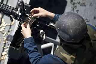 Fire Controlman Miguel Marsiglia reloads an M240G light machine gun. 