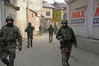 Indian troopers look on as a Kashmiri pedestrian walks along a street in Srinagar. (SAJJAD HUSSAIN/AFP/Gettymages)