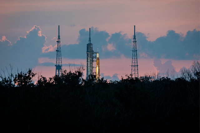 The SLS at sunrise is seen above the tree line. (Photo: NASA Artemis/Twitter)