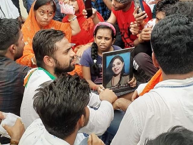 Protesters sitting with Nandini's picture