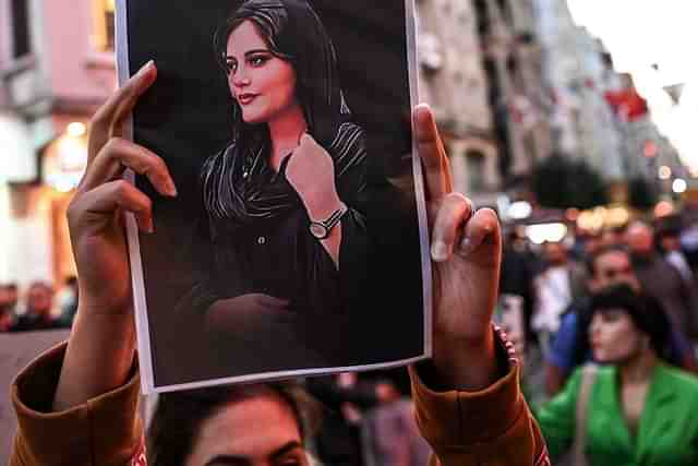 A protester holds up a portrait of Mahsa Amini.
Source: Wikimedia Commons