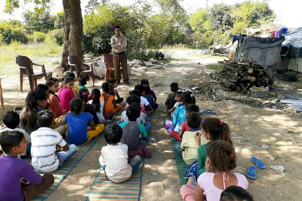A picture of the social worker, Manoj Kaushal, teaching children in a poor basti.