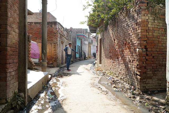 The man pointing at the open drain is Hindu