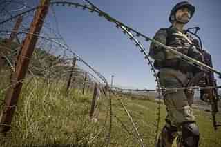 An Indian Army soldier patrols on the fence near the India-Pakistan LOC (Gurinder Osan/Hindustan Times via Getty Images).