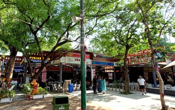 Food bazar area with a facelift: permanent roof set-ups and modern wooden, metal tables.