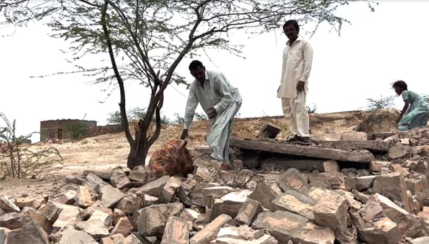 A resident shows his buried belongings in the ruins