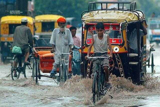 Indian commuters make their way along a waterlogged street during a heavy downpour of monsoon rain in Amritsar. (NARINDER NANU/AFP/Getty Images)