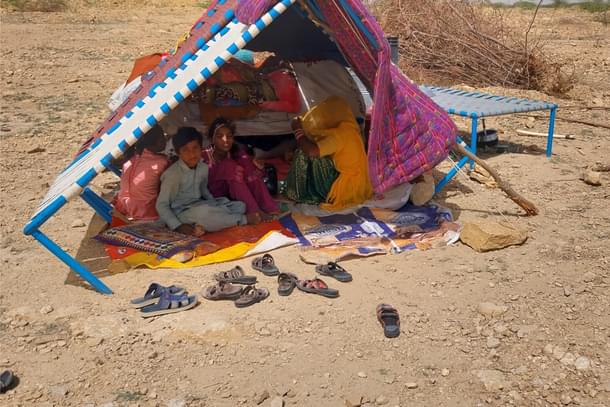 A family under the shade of a cot.