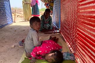 Children sitting under shade of a cot.