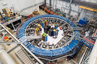 The Muon g-2 ring sits in its detector hall amidst electronics racks, the muon beamline, and other equipment. (Photo: Reidar Hahn/Fermilab)