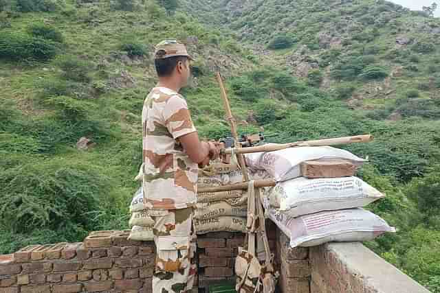 A jawan standing guard behind a temporary bunker at rooftop of the Nalhar Mahadev temple.