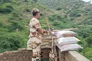 A jawan standing guard behind a temporary bunker at rooftop of the Nalhar Mahadev temple.