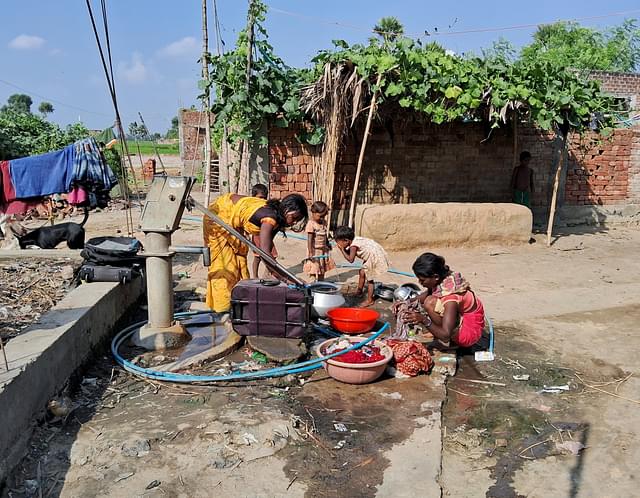 Group of residents making use of the piped connection lying outside their homes. 
(Source: Swarajya)