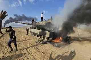 Palestinian celebrating atop a destroyed Israeli Merkava tank at opposite Gaza border fence. (Pic via AP)