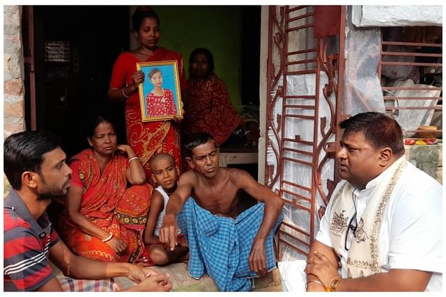SinghaBahini founder Devdutta Maji with the victim's family. The victim's mother is holding a portrait of her murdered daughter