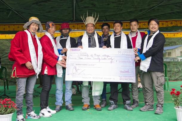 Chief Minister Pema Khandu handing over a compensation cheque to residents of Mago who gave up their land for construction of the road.