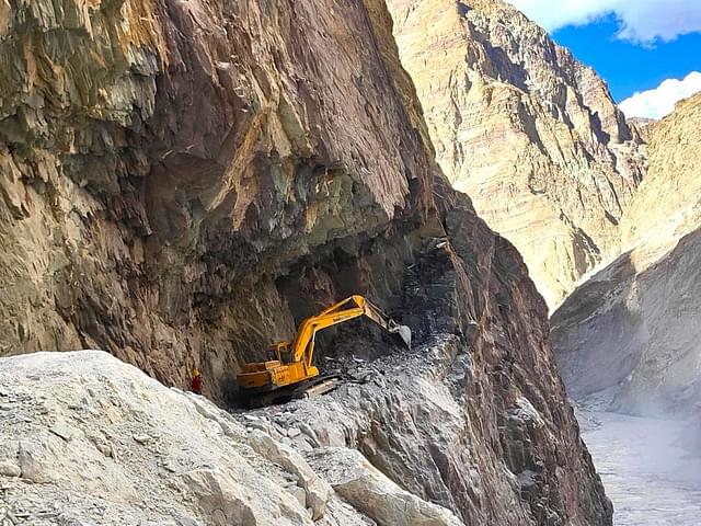 Border Roads Organisation (BRO) heavy machinery cutting thorugh the almost vertical cliff walls of hard rock in the Zanskar Valley.