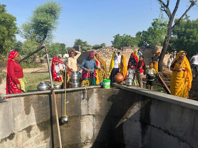 Women around the single well with water in Khurra Village. 