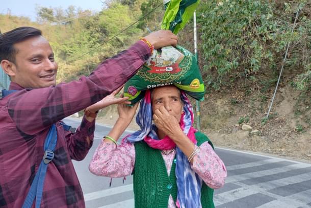 A beneficiary of Centre's free ration and Ayushman Bharat schemes in Pauri Garhwal asks a youth for help (Image credit: Sumati Mehrishi)